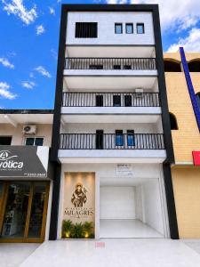 a tall white building with a garage at Pousada Milagres in Canindé