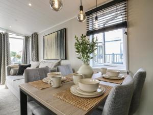 a dining room with a table with chairs and a couch at Lakewood Plot 4 in Clacton-on-Sea +18 photos