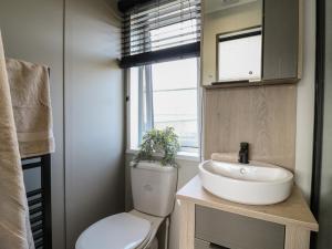 a bathroom with a toilet and a sink and a window at Lakewood Plot 4 in Clacton-on-Sea