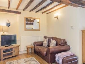 a living room with a leather couch and a tv at Bluebell Cottage - Ukc6676 in Bettws-yn-Rhôs