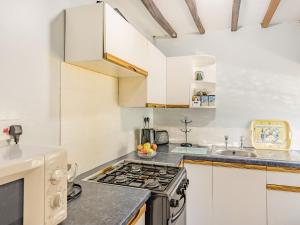 a kitchen with a stove top oven next to a sink at Bluebell Cottage - Ukc6676 in Bettws-yn-Rhôs +21 photos