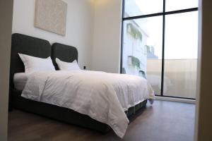 a bedroom with a white bed with a large window at Eight House villa in Jeddah