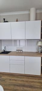 a kitchen with white cabinets and a wooden floor at Poduszka mini-hotel in Stantsiya Rokitno Volynskoye +3 photos
