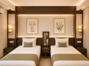 two beds in a room with two lamps and paintings at Chanaplace Lanna in Chiang Mai