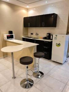 a kitchen with a white refrigerator and two bar stools at Mdmak Suites in Riyadh