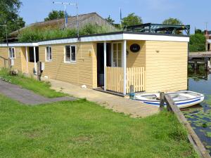 a small yellow house on the water with a boat at Ardea - Uk12695 in Stalham