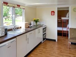 a kitchen with white cabinets and a sink and a window at Ardea - Uk12695 in Stalham