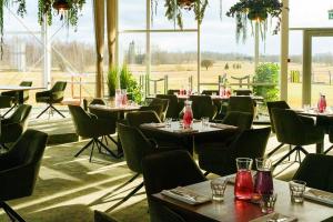 a restaurant with tables and chairs and a large window at CR x Rae Golf in Suuresta