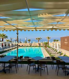 a swimming pool with tables and chairs and the ocean at Didimos Resort in Reggio di Calabria