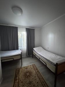 a bedroom with two beds and a rug at Guest House Kel-Kel in Bokonbayevo