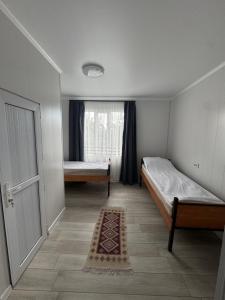 a small room with two beds and a window at Guest House Kel-Kel in Bokonbayevo +12 photos