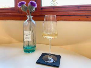 a glass of white wine next to a bottle at Innish Beag - Uk38782 in Clachan