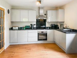 a white kitchen with white cabinets and a wooden floor at Innish Beag - Uk38782 in Clachan