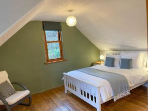 a bedroom with a white bed and a chair at Innish Beag - Uk38782 in Clachan