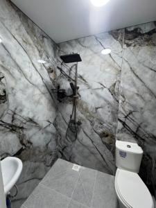 a marble bathroom with a toilet and a sink at Guest House Kel-Kel in Bokonbayevo