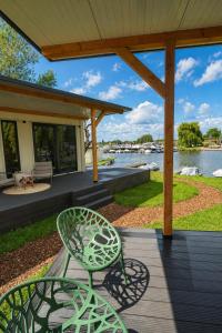 a green chair sitting on a deck next to a house at Luxury Lake Cabin in Alphen