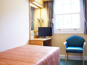 a bedroom with a bed and a tv and a chair at The Nayland Hotel in London