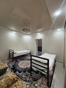 a room with two beds and a rug at Kamil Guest House in Shabdan