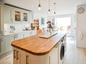 a kitchen with white cabinets and a wooden counter top at Jan Dee Cottage in Ventnor +14 photos