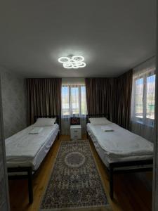 a bedroom with two beds and a ceiling at Kamil Guest House in Shabdan