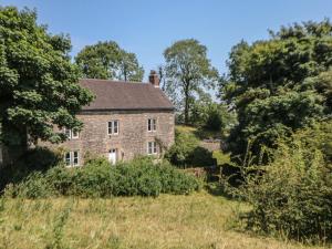 an old brick house in a field with trees at Slade House in Ashbourne