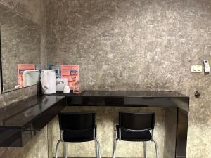 a bar with two black chairs in a room at Love Box Resort in Samutprakarn