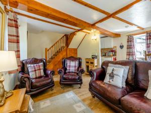 a living room with leather furniture and a staircase at Lavender Cottage - Ukc6677 in Bettws-yn-Rhôs