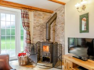 a wood stove in a living room with a tv at Lavender Cottage - Ukc6677 in Bettws-yn-Rhôs