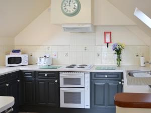 a kitchen with blue cabinets and a clock on the wall at Solace - Ukc2122 in Stalham