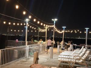 a deck with white chairs and lights at night at ลุงชีพบ้านพัก เกาะล้านLoongcheeb House in Ko Larn