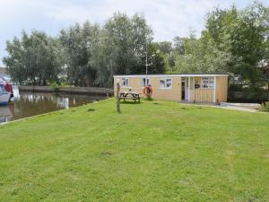a tiny house sitting on the grass near a river at Halcyon - Uk12696 in Stalham