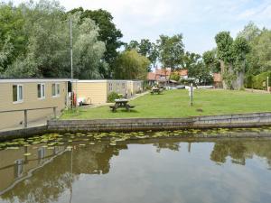 a caravan park with a picnic table and a pond at Halcyon - Uk12696 in Stalham