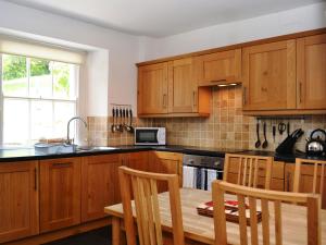 a kitchen with wooden cabinets and a table with chairs at Croft Cottage in Braithwaite
