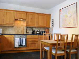 a kitchen with wooden cabinets and a table with chairs at Croft Cottage in Braithwaite