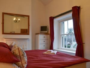 a bedroom with a bed with a mirror and a window at Croft Cottage in Braithwaite