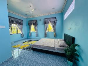 a bedroom with blue walls and a bed with windows at Taman Darul Salam Homestay Pasir Puteh in Pasir Puteh