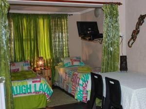a bedroom with two beds and a table and chairs at Art Guest House in Lutzville