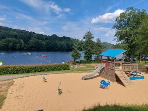 ein Spielplatz mit einer Rutsche im Sand neben einem See in der Unterkunft Baloe in Manderfeld