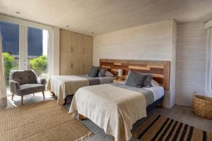 a bedroom with two beds and a chair at Casas Punta Costanera in Pichilemu