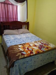 a bed with a blue blanket with flowers on it at Casa simples em cunha in Cunha