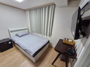a bedroom with a bed and a desk and a television at Minimo Stay in Pyeongtaek