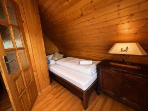 a small bed in a wooden room with a lamp at Chata Medvedík in Turík
