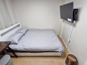 a small bedroom with a bed with a tv on the wall at Minimo Stay in Pyeongtaek