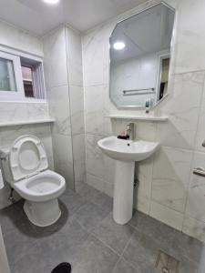 a white bathroom with a toilet and a sink at Minimo Stay in Pyeongtaek