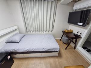 a small bedroom with a bed and a television at Minimo Stay in Pyeongtaek +7 photos