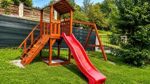 a wooden playground with a slide in the grass at Chata Medvedík in Turík