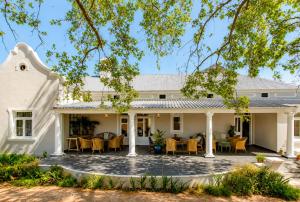 an image of a white house with tables and chairs at Banhoek Corner Guesthouse in Stellenbosch