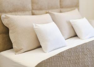 three white pillows sitting on top of a bed at apartman STUDIO ELEGANCE in Bečej