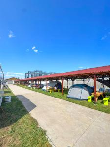 a long building with tents on the grass at Relax by the Sea Camping next to Nibiru in Costinesti +22 photos