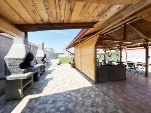 an outdoor patio with a fireplace and a wooden roof at Relax by the Sea Camping next to Nibiru in Costinesti